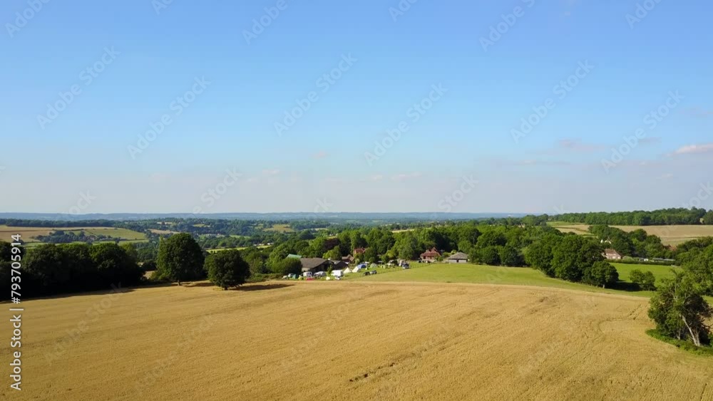 Kent Countryside, UK - Drone flies over wheatfield at sunset towards small campsite Kent Countryside, UK - Drone flies over wheatfield at sunset towards small campsite