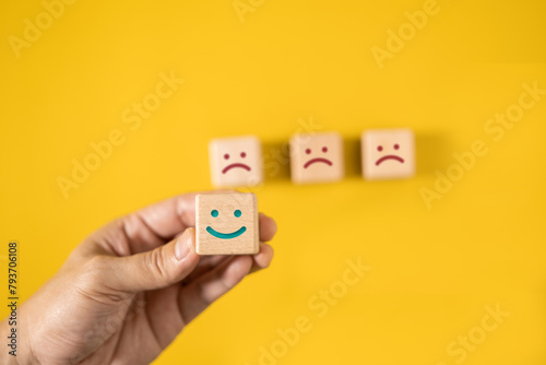 Man's hands picking up wooden dice with smiley faces, concept of choosing positive emotions over negative ones.