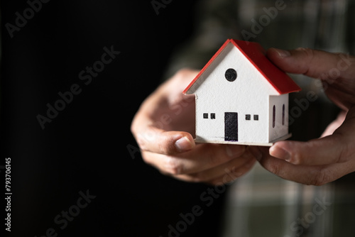 Man hand holding a house model in his hand,The concept of owning a house or mortgaging real estate.	