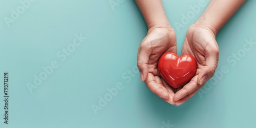 two hands holding a red heart on a light blue background photo