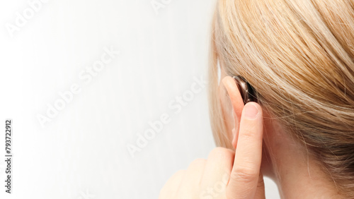 Woman wearing digital hearing aid. Person with disability from the back, medical support, listening and healthcare technology. Deafness treatment, hearing solutions. Place for text.