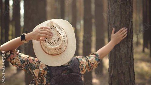 Girl in dress walking in greenwood . Woman in hat walking pine forest	 photo