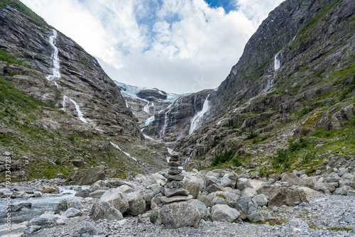 View of Jostedal Glacier or Jostedalsbreen in Norway is the largest glacier in continental Europe. Big waterfalls from gray brown slopes, white snow and glacier turquoise ice. Delightful glacier view