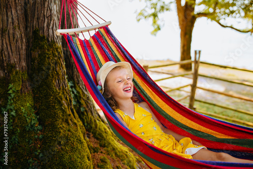 A laughing child in a bright hammock outdoors. Relaxation and positive emotions in nature away from the city.