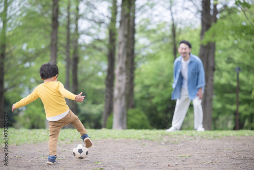 サッカーボールを蹴る男の子と遊ぶ父親　顔無しの後ろ姿 photo