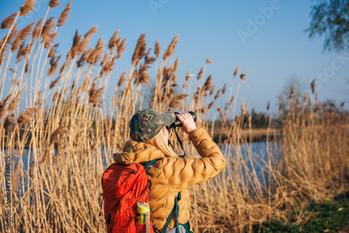 Bird watching. Woman with binoculars looking for wildlife animals and birds at lake © encierro