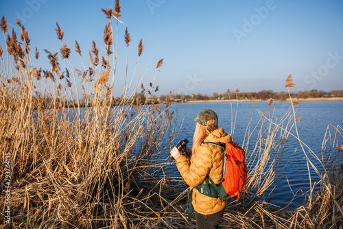 Bird watching. Woman with binoculars looking for wildlife animals and birds at lake © encierro