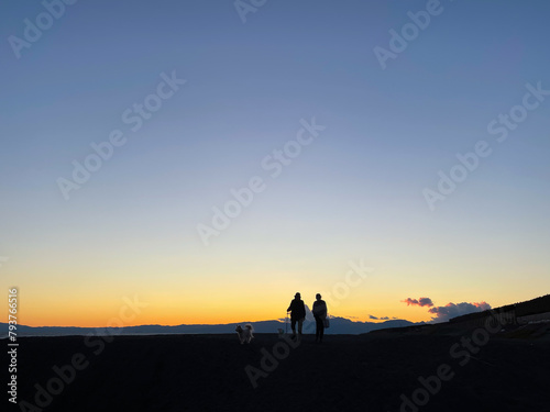 湘南海岸の夕日が沈む茅ヶ崎で犬と散歩をする人のシルエット © D maborosi