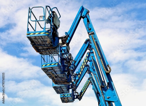 Wallpaper Mural Blue aerial work platforms of cherry pickers in a row against blue sky with clouds	 Torontodigital.ca