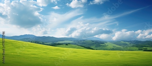 Green field, majestic mountains, cloudy sky