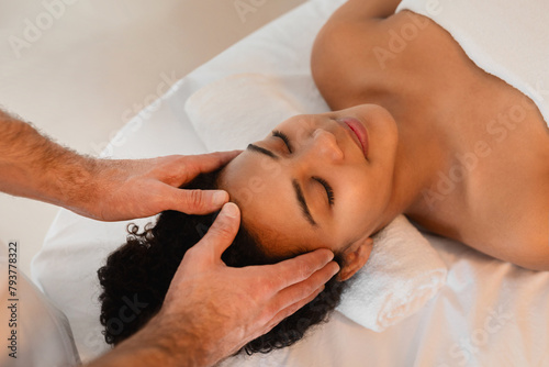 Therapist providing temple massage to relaxing woman