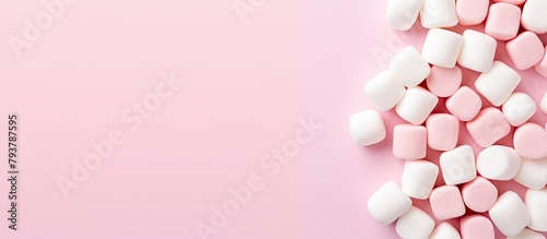 A heap of fluffy white marshmallows on a pink surface