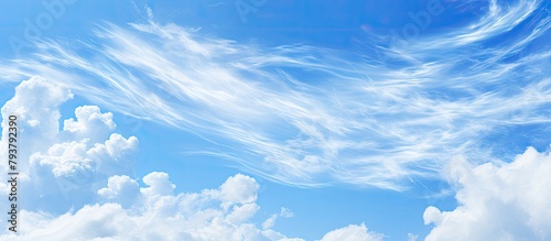 Plane flying in clear blue sky with fluffy clouds
