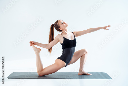 Fit young woman posing showing great balance and stretch in a well-lit bright studio. Great for presentation of healthy lifestyle related to choreography and fitness.