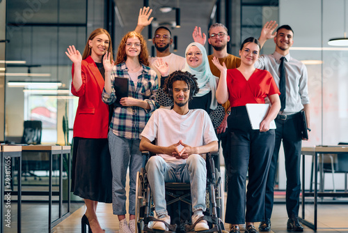 A diverse group of young business people walking a corridor in the glass-enclosed office of a modern startup, including a person in a wheelchair and a woman wearing a hijab