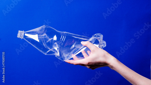 A woman's hand holds a deformed plastic bottle