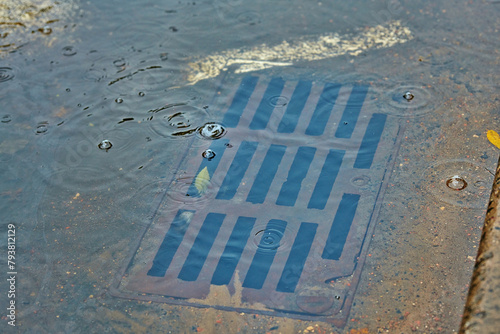 Flooded sewer drain hole, clogged drains. Blocked drainage system flooded with water during rain. Rain water flows up out of clogged drain, causing flood. Selecticve focus