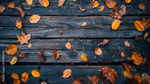 Fallen autumn leaves scattered on a dark stained wooden deck, capturing the essence of the fall season.