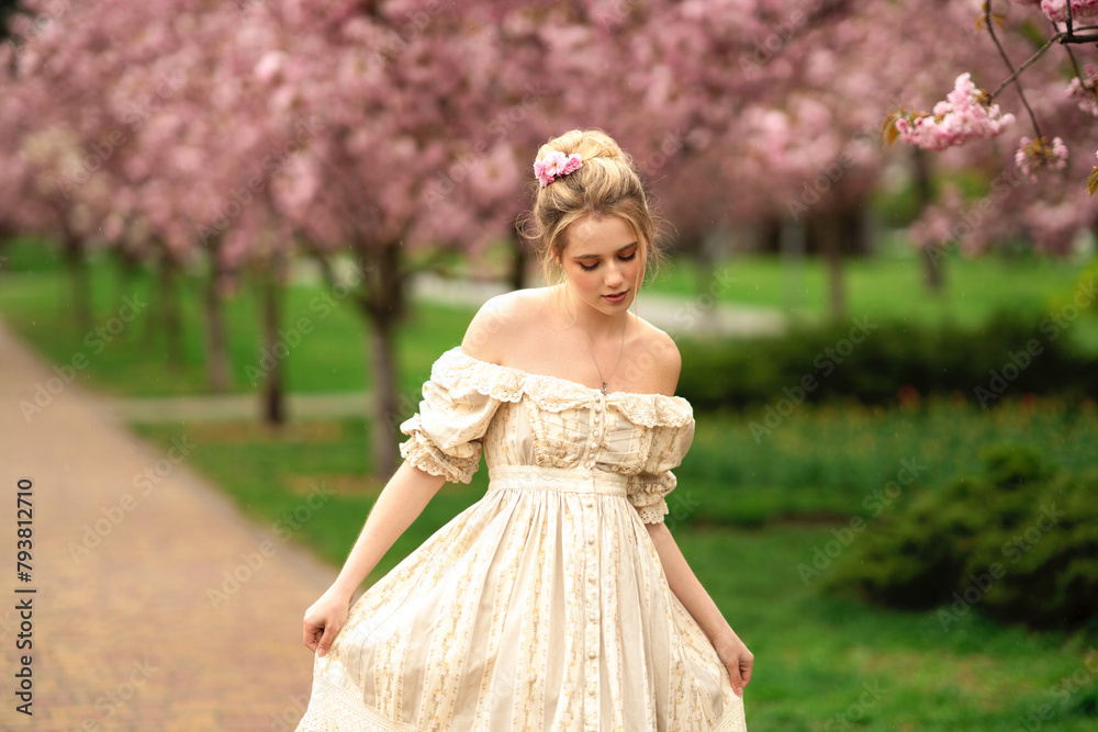 Pretty young blonde girl  in vintage lace dress  standing in spring park near pink blossom flowers. Tenderness romantic  model posing 