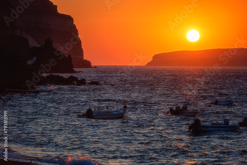 Amazing sunset seascape on Santorini island, scenic view of the Aegean sea, colored sky with sun and volcanic cliffs, Akrotiri beach, Cyclades, Greece. Outdoor travel background, summer holidays