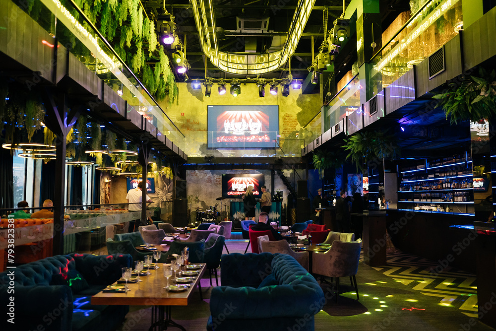 Obraz premium A restaurant with a large screen TV and a lot of seating. The TV is showing a game.
