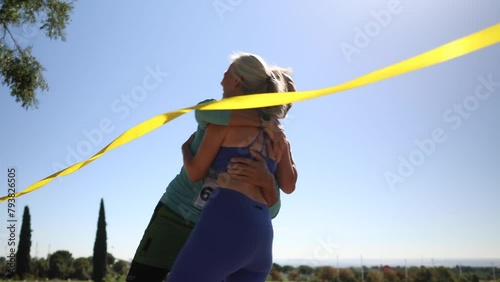 An elderly couple doing a marathon hug each other, very happy to cross the finish line of the race.