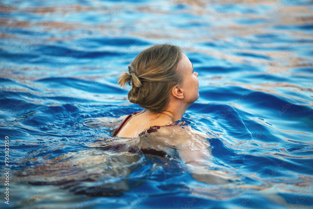 A girl swims in a pool outdoors.