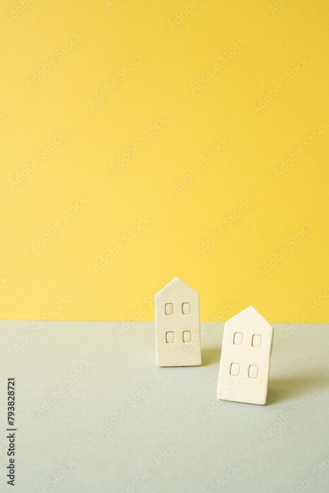 Wooden house model on gray and yellow background. Real estate concept