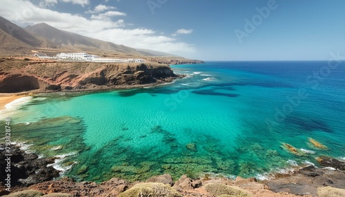 view of the coast of island, Jumping girl on beach. Smilling blonde girl enjoying sandy beach, looking at crystalline sea in Canary Islands. Concept of beach summer vacation with kids.