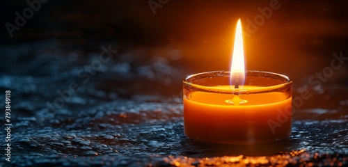 A lit candle casting a warm glow against a dark backdrop.