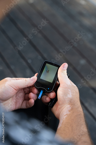 Men checking their sugar levels using a lancet pen and a glucometer in the city