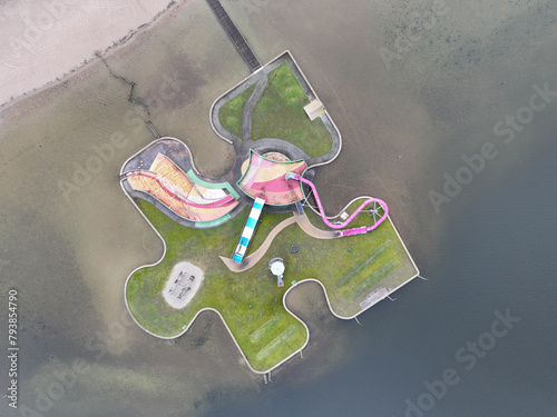 Aerial drone view children playground in the form of a puzzle piece. Colorfull recreation area with slide, swing and climbing racks at Maarsseveens Plassen , The Netherlands.