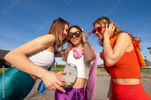 tre ragazze felici che ascoltano musica in esterna photo