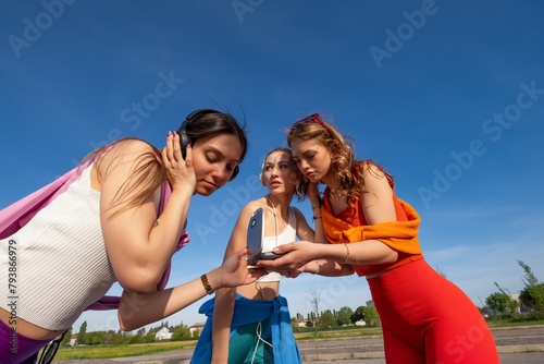 tre ragazze felici che ascoltano musica in esterna photo