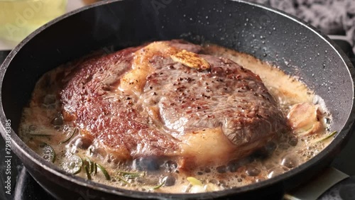 delicious juicy geef steak meat cooking on a pan with garlic and rosemary in melted butter. Process of making perfect steak at home photo