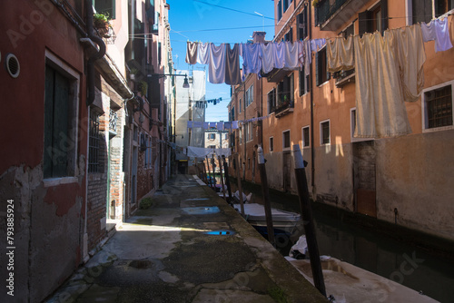 Uno stretto canale di Venezia con dei panni stesi ad asciugare e illuminato da un raggio di sole photo