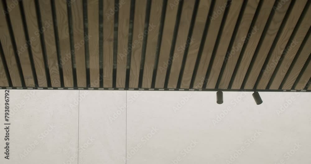 Close-up of a stylish interior featuring a linear wooden ceiling with ...