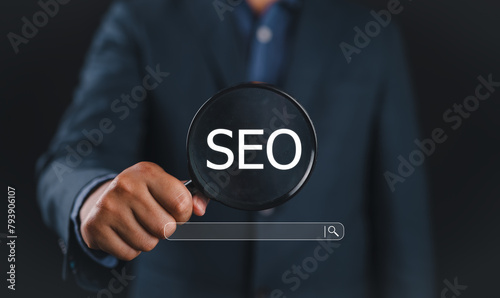 Businessman using magnifying glass focus to SEO icon to analyze SEO search engine optimization for promoting ranking traffic on website and optimizing your website to rank in search engines.