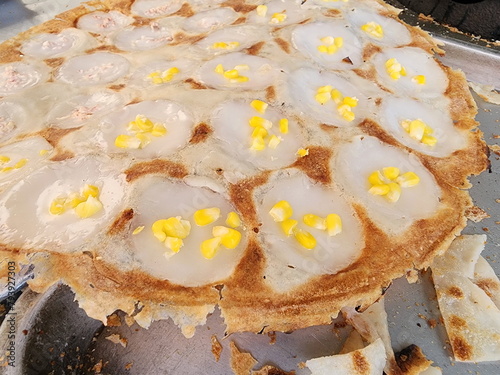 Thai Coconut Pudding Pan or Khanom Krok Pan is Traditional Thai desserts. Baker sprinkling chopped sweetcorn and taro into the uncooked dough. Traditional Thai dessert made from flour, sugar, coconut