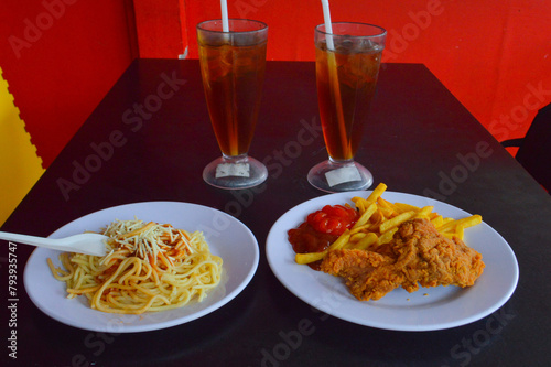 Simple Fast Food Meal Of Fried Chicken, French Fries, Spaghetti, With Two Glasses Of Iced Tea On The Dining Table Of The Eatery