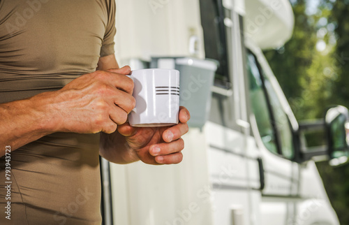 A Man with a Coffee Cup in His Hands Staying Next to His Camper Van