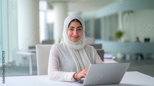 Middle East woman or girl works with on a laptop in the office or a bright and open workspace. Student or remote teacher is working in online education, flexibility of remote work