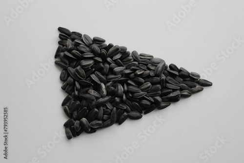 A triangle laid out from sunflower seeds fried with salt on a white surface top view
