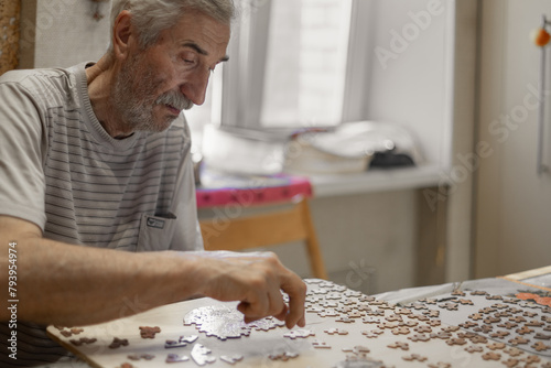 Senior caucasian man working on a puzzle,  playing  jigsaw puzzle as dementia therapy