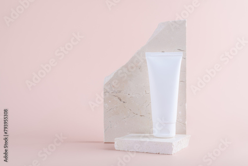 White plastic tube mockup for medicine or cosmetics on marble podium on pastel pink background. White plastic tube. Skin care product mockup, copy space
