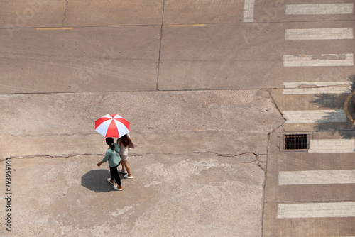 In the hot sun, there were still people walking on the road with umbrellas.