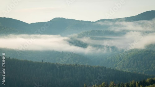Time lapse video of morning fog flowing in mountains. Wet morning in mountains, sun goes up and illuminates the walleys photo