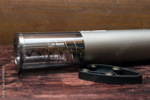 Device automatic opening of wine bottles, electric corkscrew on a dark wood background.