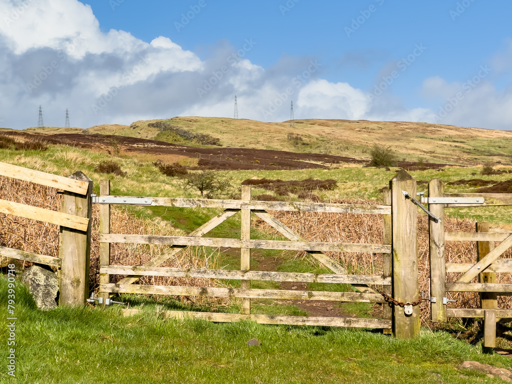 Gate or wooden fence with dirt foot path, track leading to the Scottish highlands, Kilpatrick hills. Sunny but windy typical Scottish weather with sunshine and rain