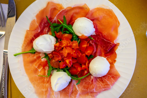 Cuisine of Emilia-Romagna region, Caprese salad with Prosciutto crudo, prosciutto di Parma, mozzarella cheese and tomatoes, lunch in Parma, Italy photo